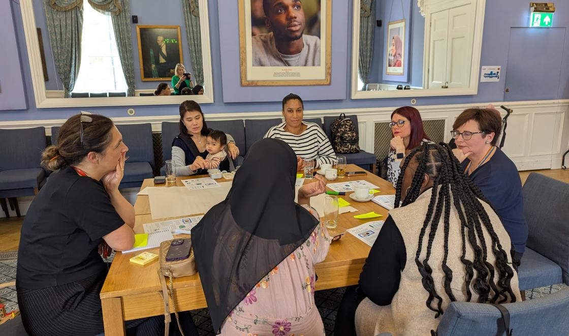 A group of women public involvement members and researchers gather around a table to discuss the RELAX study 