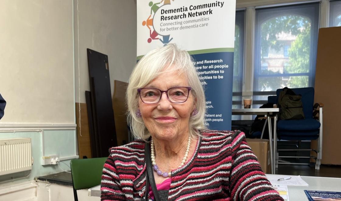 An image of Pauline Jones in front of the Dementia Community Research Network banner