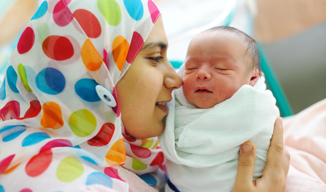 Muslim woman wearing hijab holding baby