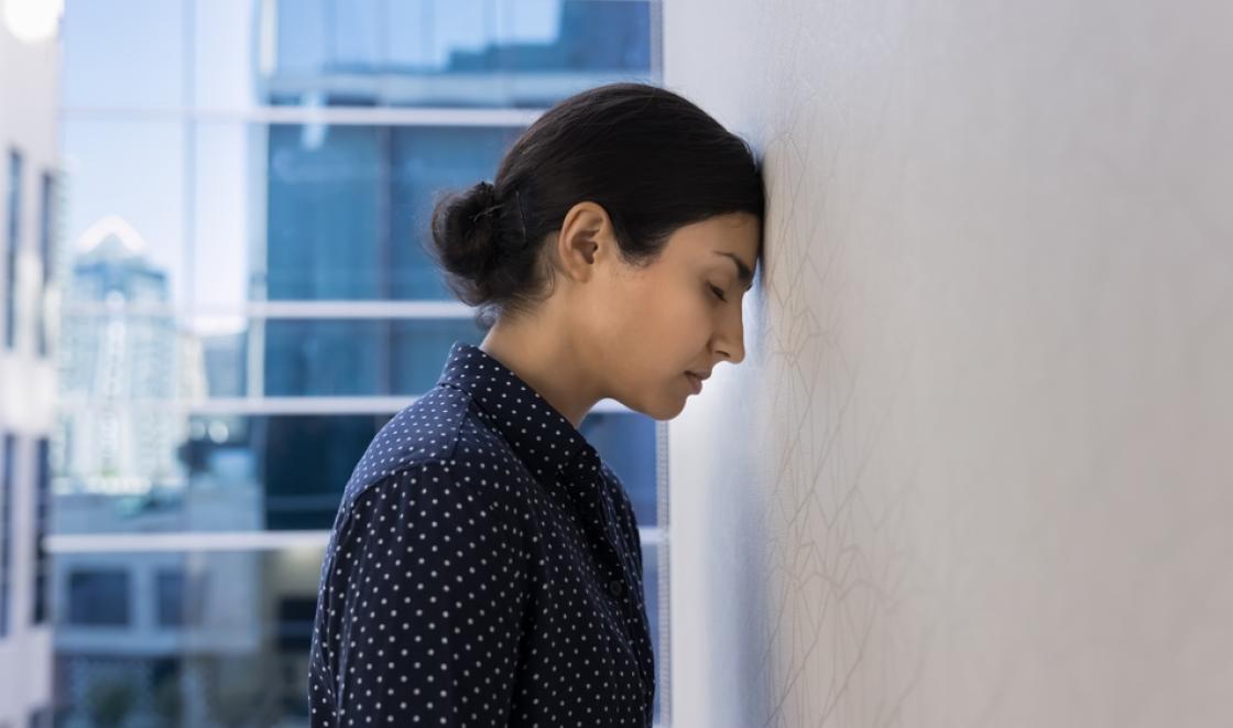 I woman leaning her head against a wall